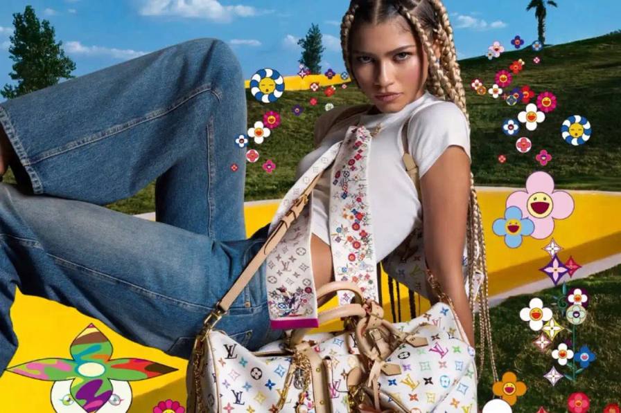 Zendaya poses in casual denim and a white crop top against a green screen background with Murakami's floral motifs. She wears a white Louis Vuitton x Murakami bandeau and holds a matching Keepall bag