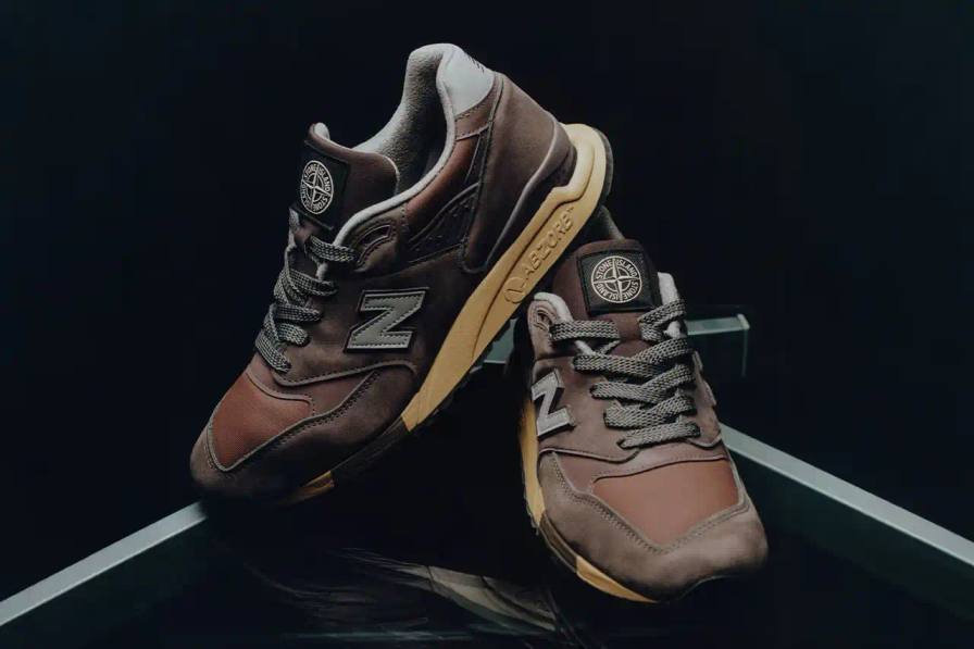 New Balance 998 sneakers redesigned by Stone Island, featuring polyurethane-coated cotton canvas in mauve, plum, and copper tones with reflective details.