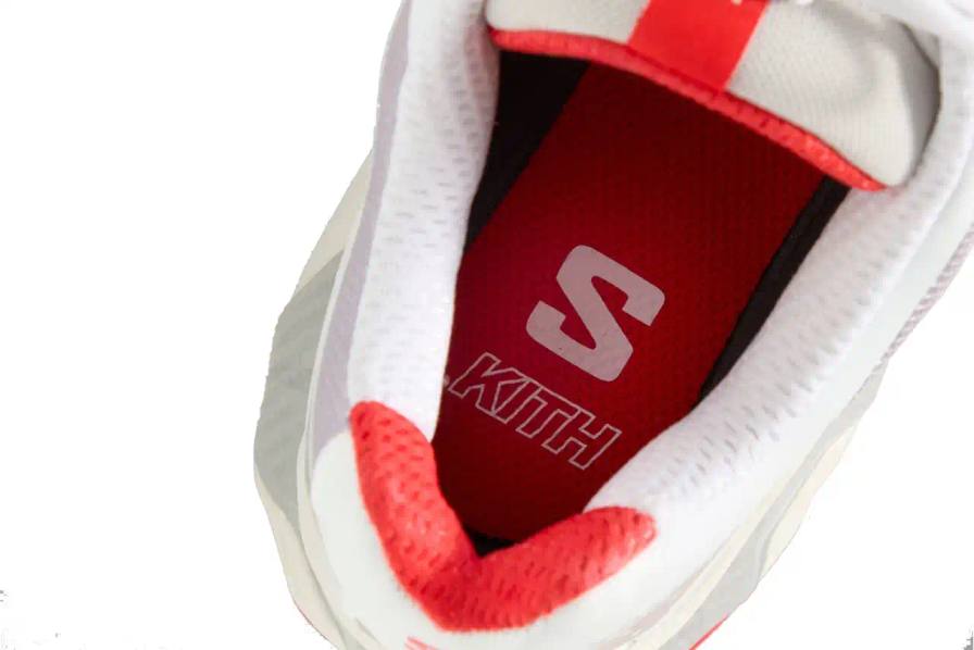 Kith x Salomon XT-Voyager sneaker shown from side angle, featuring blue, grey, white and red colorway with distinctive zipper closure system.