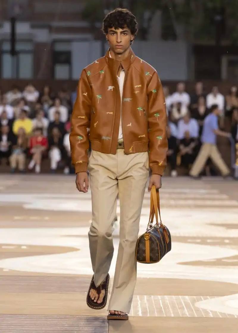 image about Louis Vuitton's Spring/Summer 2026 men's collection presented by Creative Director Pharrell Williams. The collection draws inspiration from contemporary Indian style, features warm sun-bleached colors, and incorporates archival leather goods originally created for Wes Anderson's 2007 film "The Darjeeling Limited." The show took place at Centre Pompidou with staging by Studio Mumbai architects.