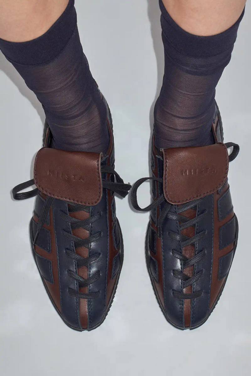 Photo about Miista's new Nikoletta sneaker. Describes the low-profile design inspired by 1980s athletic footwear, construction details including goat leather and fold-over tongue, available colors (black, brown/navy, black/white), price ($415), and where to purchase. Includes quote from creative director Laura Villasenin about the brand's philosophy of continuous improvement and craftsmanship.