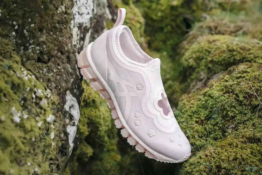 an image describing the new ASICS and Cecilie Bahnsen collaborative sneaker release. The design modifies a running shoe into a floral Mary Jane style in pink and black colorways.
