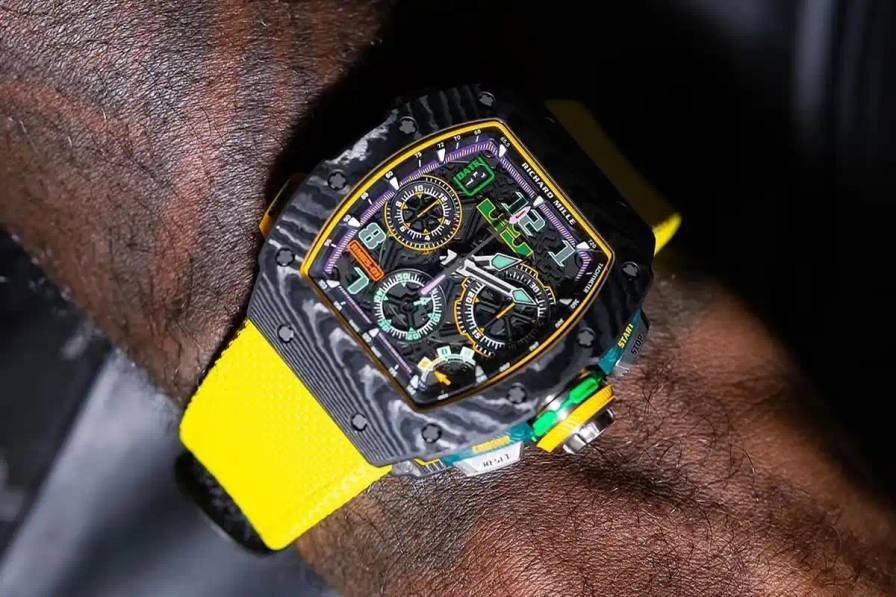 image reports on a luxury watch collaboration between basketball player LeBron James and Swiss manufacturer Richard Mille. The timepiece incorporates Los Angeles Lakers team colors including yellow, purple, and green elements throughout its design. Key details include the $450,000 price point, production limitation of 150 units, and specific material choices like Quartz TPT construction. The watch features James' personal signature and logo placement as design elements. The article provides technical specifications about the watch's construction, materials, and distribution through authorized dealers.