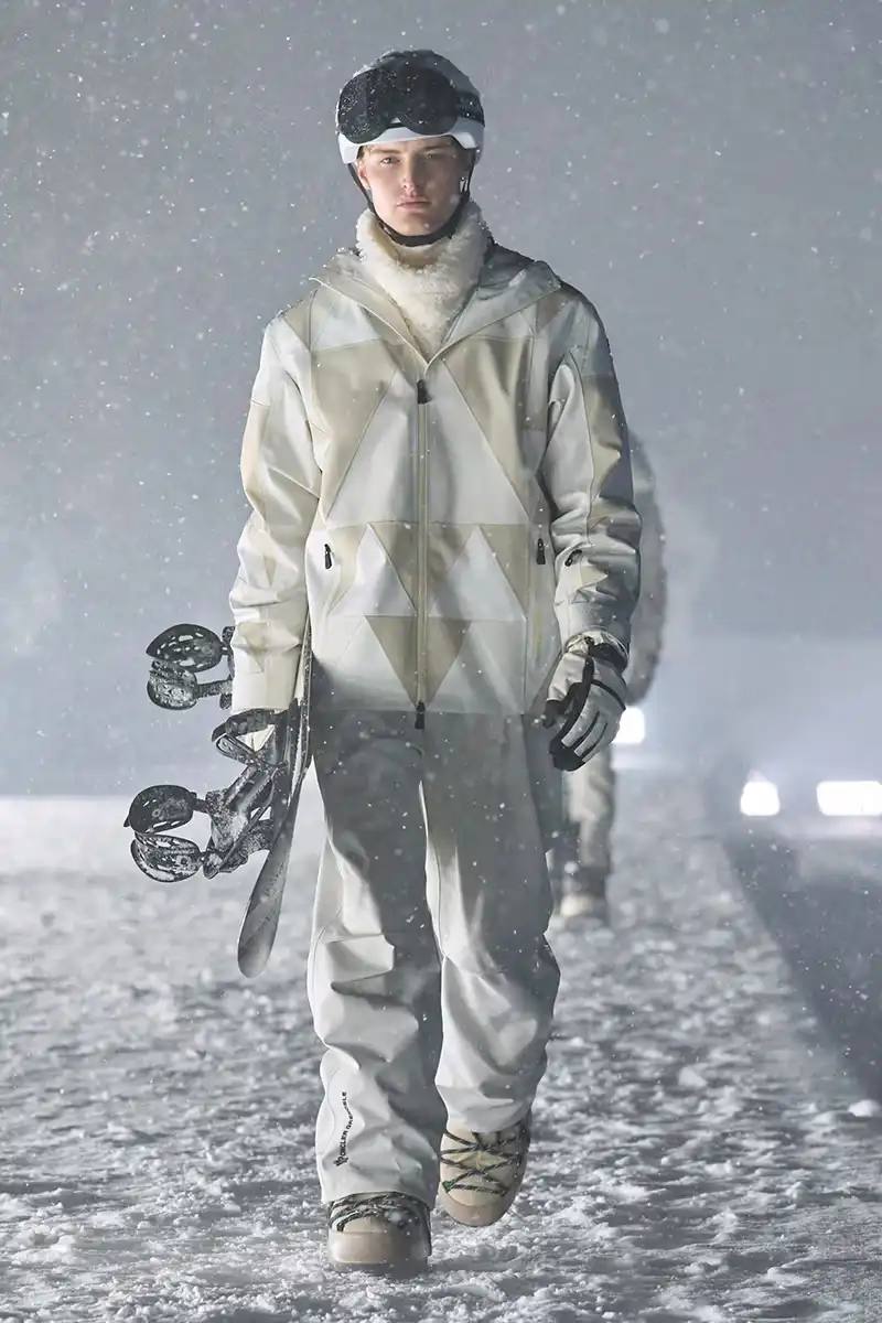Moncler's Fall/Winter 2025 Grenoble collection showcase held at Courchevel Altiport in the French Alps. It details how the runway show transformed Europe's highest airport into a fashion venue at 2,008 meters above sea level. The article outlines the collection's 140 looks that blend urban style with mountain functionality, featuring innovative materials like denim and canvas alongside traditional winter textiles. It mentions the craftsmanship details including embroidery and intarsia patterns on ski suits. The article also notes celebrity attendees and a special snowboard collaboration with Shaun White's WHITESPACE brand. The content is organized in paragraphs describing the event setting, collection details, and notable highlights