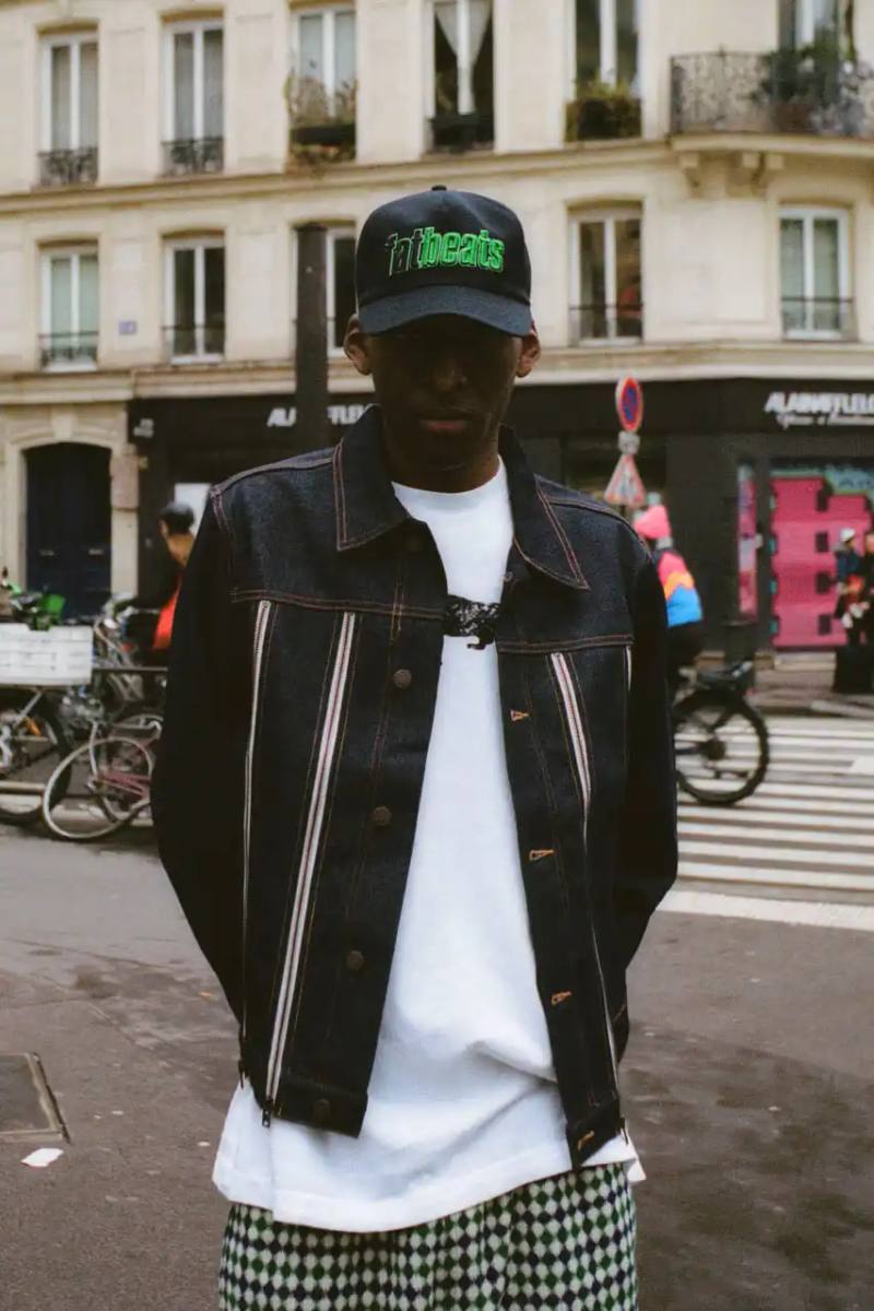 Quinn Dunziellas PLEASURES Spring/Summer 2025 lookbook photograph showcases models wearing the new collection against Parisian backdrops. Featured items include a Realtree camo jacket, leopard print blazer, and holographic-lined outerwear pieces.