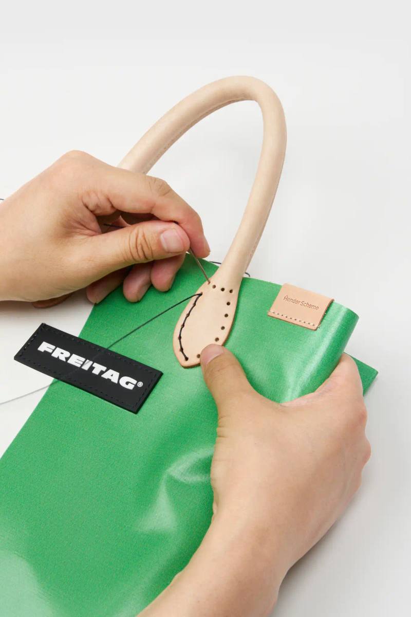 HENDER SCHEME AND FREITAG UNITE FOR UPCYCLED BAGS image of Tokyo-based Hender Scheme collaborates with Zurich bag maker FREITAG to create limited edition shoppers featuring leather handles made from production waste, replacing original truck tarp straps.