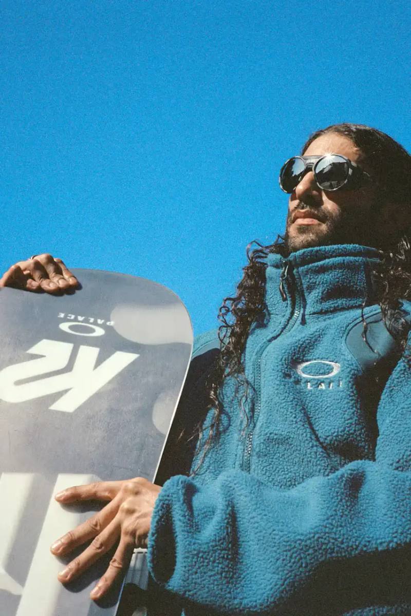 The Palace x Oakley winter collection lookbook features two Palace skate team members, Juan Saavedra and Charlie Birch, modeling the range of technical puffa jackets, snow pants, fleece zip-ups, and co-branded accessories like snowboards, goggles, and sunglasses.