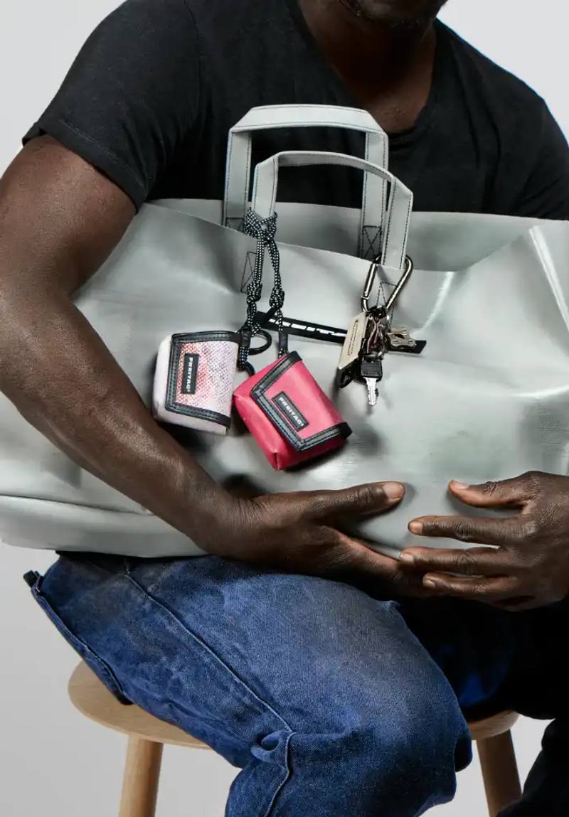 image about FREITAG's new Lucky Trucking Charms collection, which repurposes production waste from truck tarps into bag accessories and keychains.
