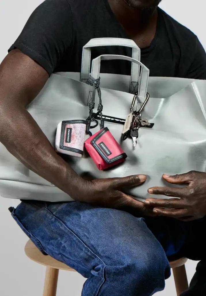 FREITAG TRANSFORMS PRODUCTION WASTE INTO BAG CHARMS image about FREITAG's new Lucky Trucking Charms collection, which repurposes production waste from truck tarps into bag accessories and keychains.