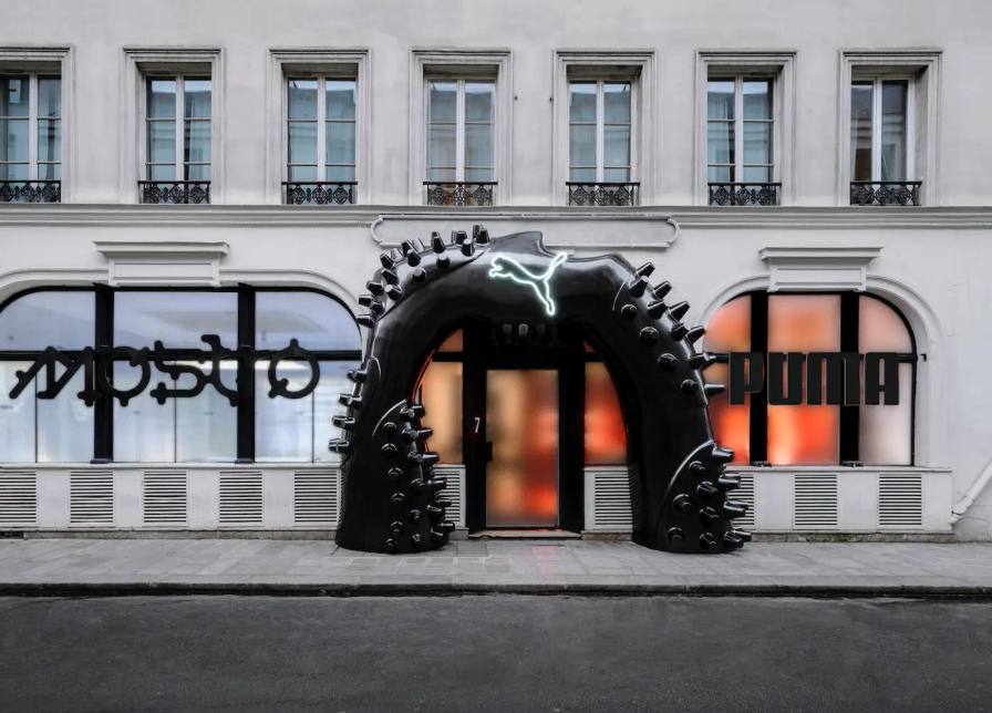 Image shows PUMA's Paris Fashion Week event promotional visual, highlighting collaborative design, urban culture, and the Mostro sneaker with diverse creative elements in the background.