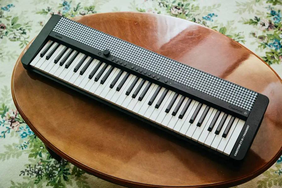 Black and white Casiotone CT-S1 keyboard with houndstooth patterned speaker covers, featuring fragment design's double lightning bolt logo above the C8 key and black control knobs.