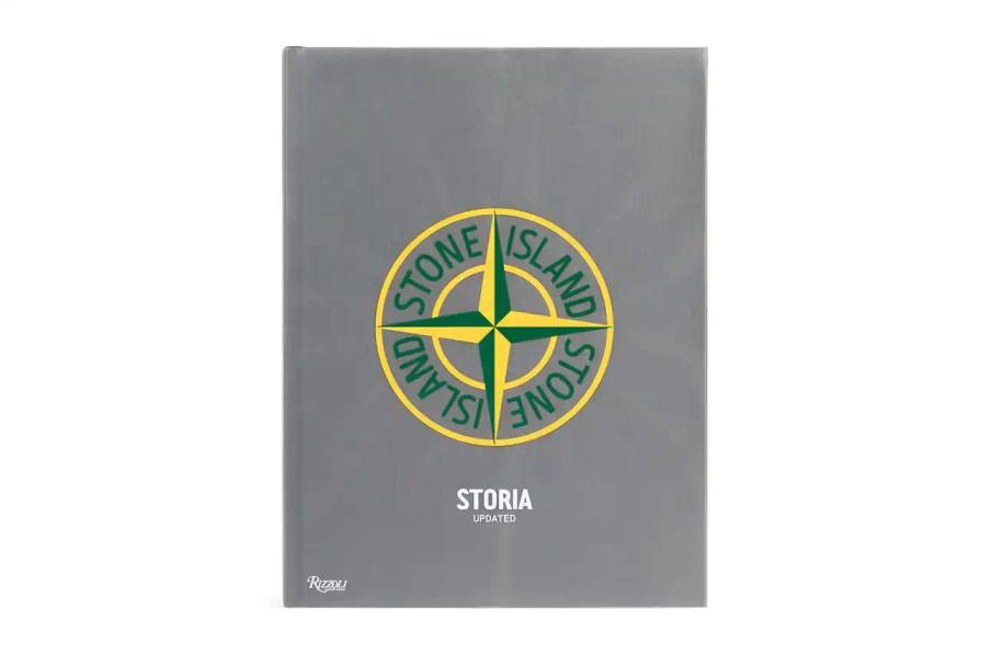 The cover of the "Storia: Updated" book by Stone Island, a full-color monograph published by Rizzoli New York. The book's title and Stone Island's logo are prominently displayed against a textured background.
