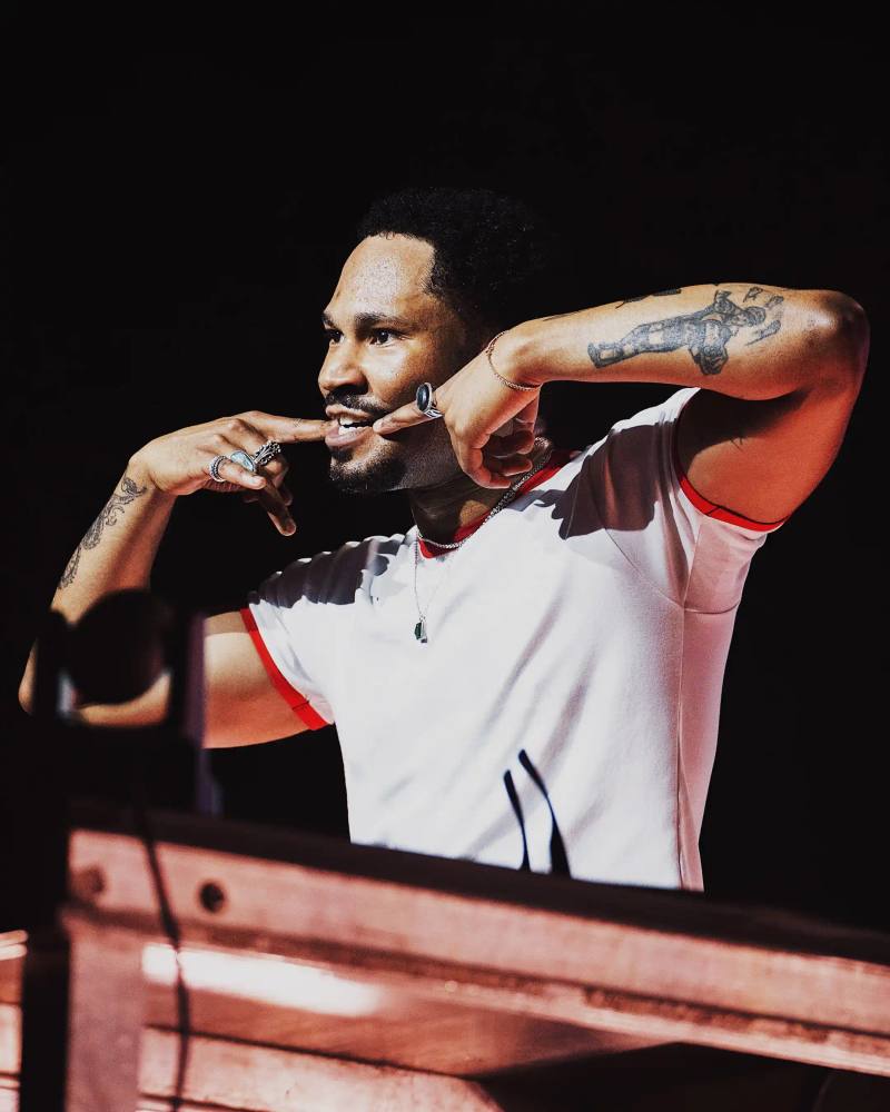 Photo of Haitian-Canadian producer Kaytranada, chronicling his rise from SoundCloud remixes to Grammy-winning artist. It details his musical style, major career milestones including his debut album "99.9%" and follow-up "BUBBA," his iconic Boiler Room performance, and his impact on electronic music culture. The article concludes with mentions of his current European tour and recent Milan performance. Content is structured chronologically with clear paragraphs describing his career development, musical innovations, and cultural significance.