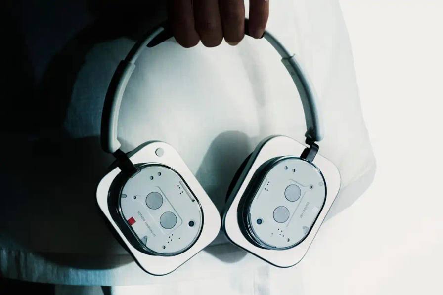 image about Nothing's release of two new products: the Phone (3) smartphone and Headphone (1) over-ear headphones. The Phone (3) features a 6.67-inch display, Snapdragon 8s Gen 4 processor, and new Glyph Matrix micro-LED system. Camera specifications include triple 50MP rear cameras and 4K video recording. The Headphone (1) is Nothing's first over-ear audio product, developed with KEF, featuring 40mm drivers, adaptive noise cancellation, and 80 hours battery life. Both products are available for pre-order July 4 and general sale July 15. The Phone (3) starts at £799 GBP in black or white with storage options of 12GB/256GB and 16GB/512GB. The Headphone (1) costs £299 GBP in black or silver finishes.