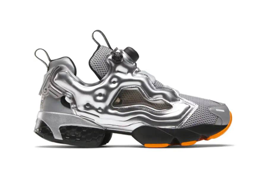 A pair of Aries x Reebok Instapump Fury 94 sneakers featuring a metallic silver upper with orange accents, showcasing the innovative laceless design and split-sole silhouette against a clean background.