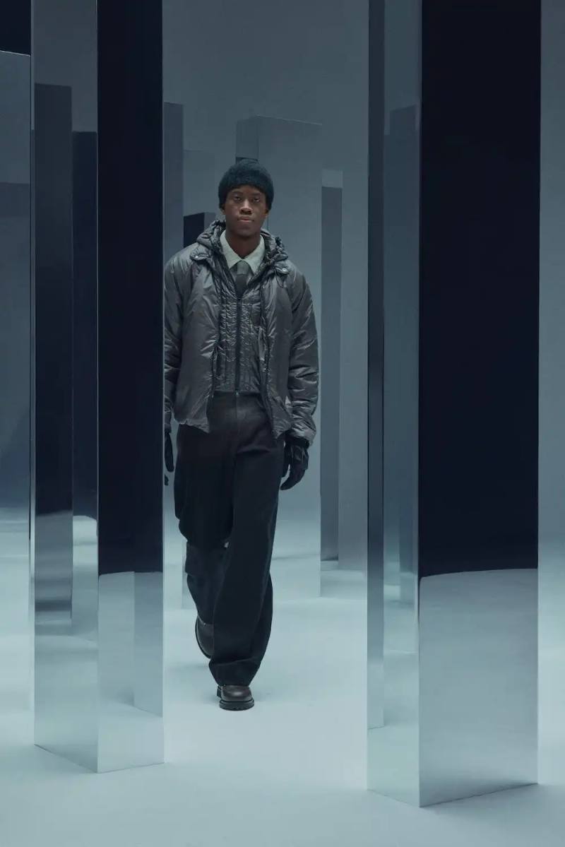 J.L-A.L Fashion runway image showing deconstructed men's suits with fluid silhouettes, layered jersey fabrics, and unconventional wool textures, inspired by surrealist animation and challenging traditional menswear archetypes.
