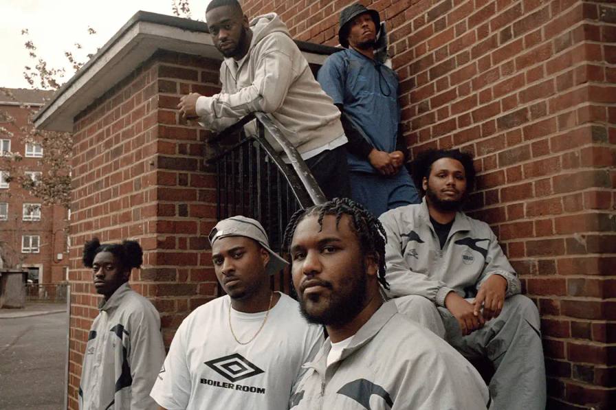image of Umbro's third collaboration with Boiler Room, featuring a clothing collection modeled by UK artists from South London. The collection includes grey tracksuits with black accents, co-branded t-shirts, football jerseys, and hoodies. All items photographed by Simon Wheatley in Lewisham and will be available from both brands on May 15.