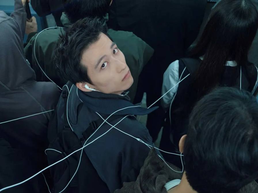A campaign photo shows a model tied in white cords over black outerwear alongside another model looking back in white technical strings.