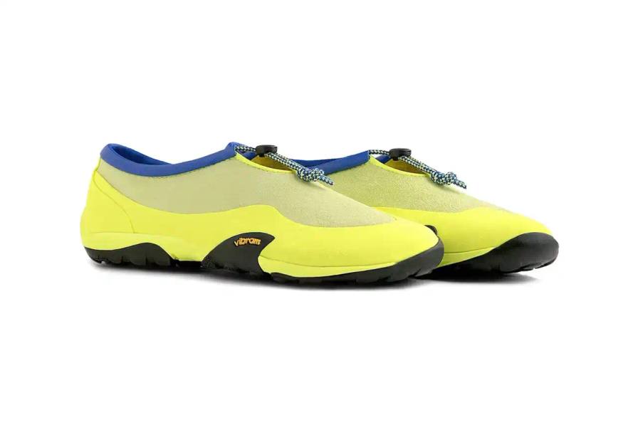 image of the upcoming release of three New Balance MT10T sport slip-ons by Aimé Leon Dore. The footwear features sock-like uppers with leather trim, drawstring closures, and Vibram outsoles. Available in neon yellow, olive green, and black with red/sage green accents, the collection launches May 16th exclusively through Aimé Leon Dore, with pricing to be announced. The article details the design elements, color options, and release information for this Summer 2025 footwear collaboration.