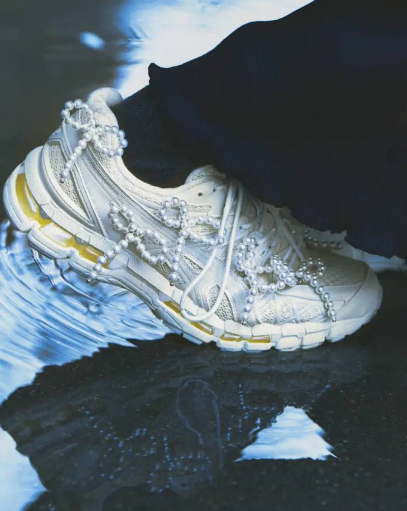 A photograph shows a pair of ASICS GEL-KAYANO 20 sneakers modified with sculptural jewelry elements like pearls and floral motifs.