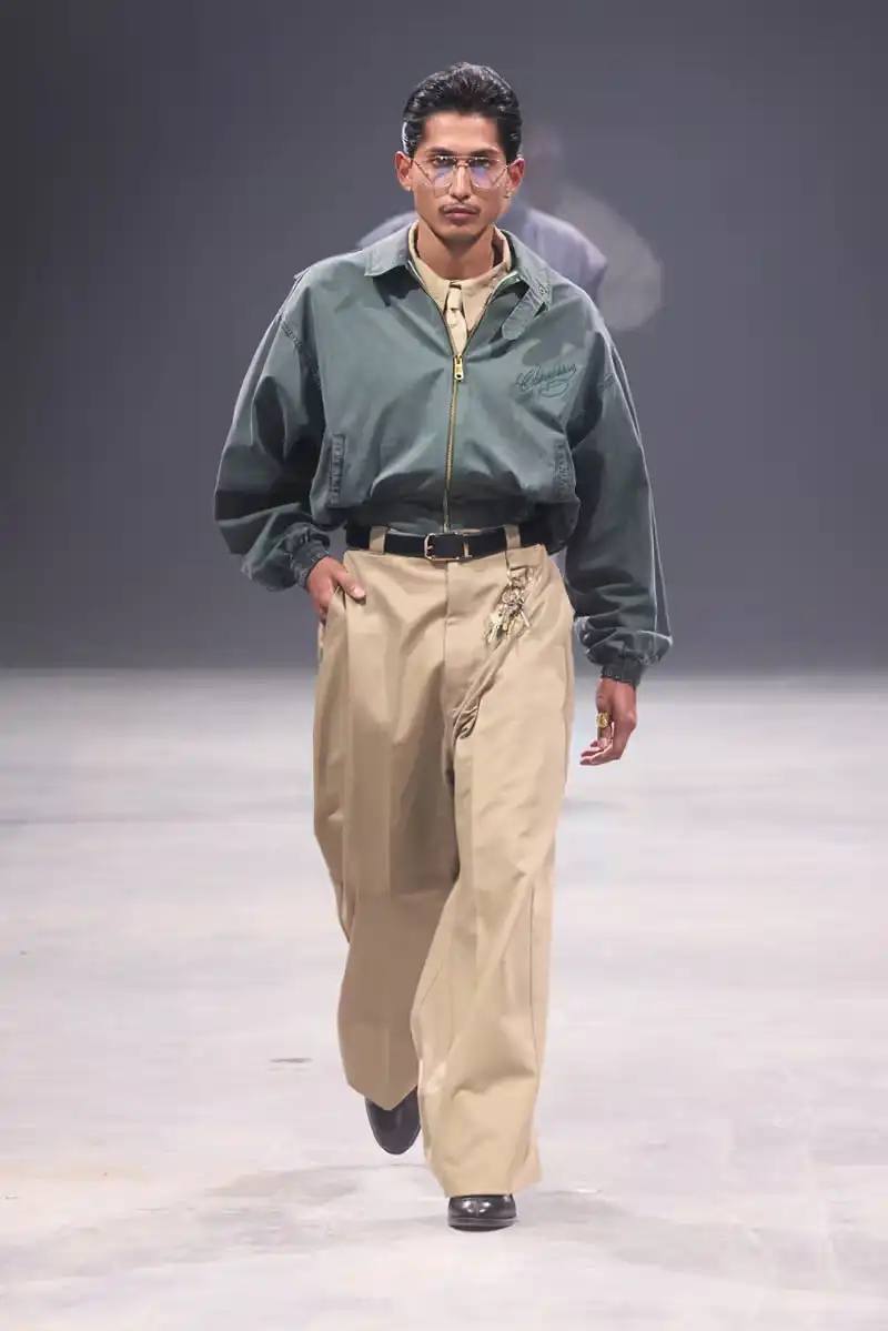Willy Chavarria Models walk the runway at Willy Chavarria's SS25 'América' show, wearing dramatic workwear-inspired designs against an industrial backdrop