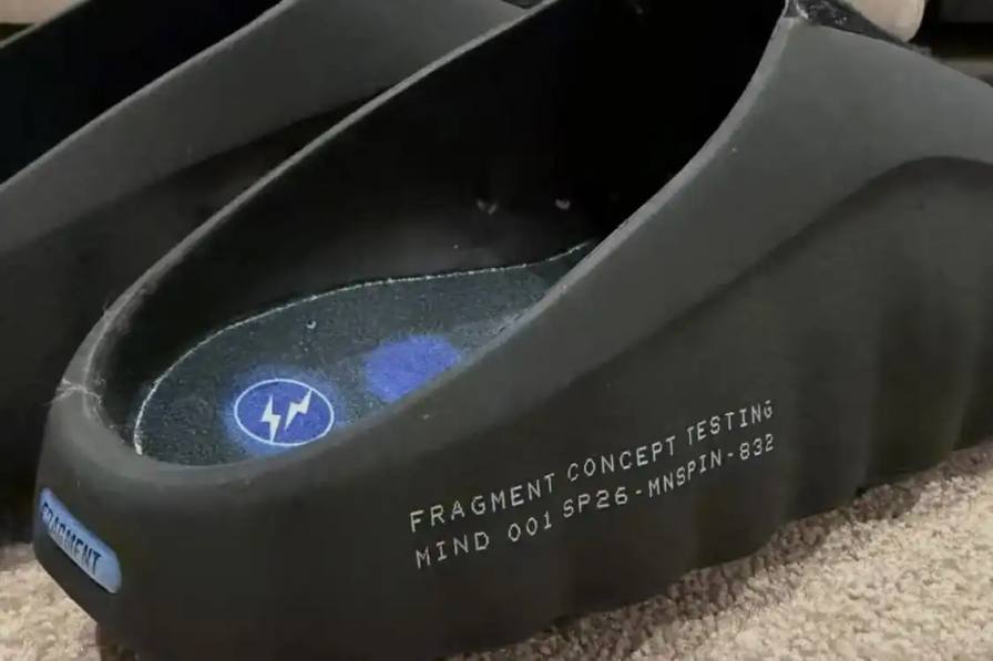 Fragment design and Nike collaborate on the Mind 001 mule featuring a thick ridged outsole, black rubber and neoprene upper, and royal blue accents.