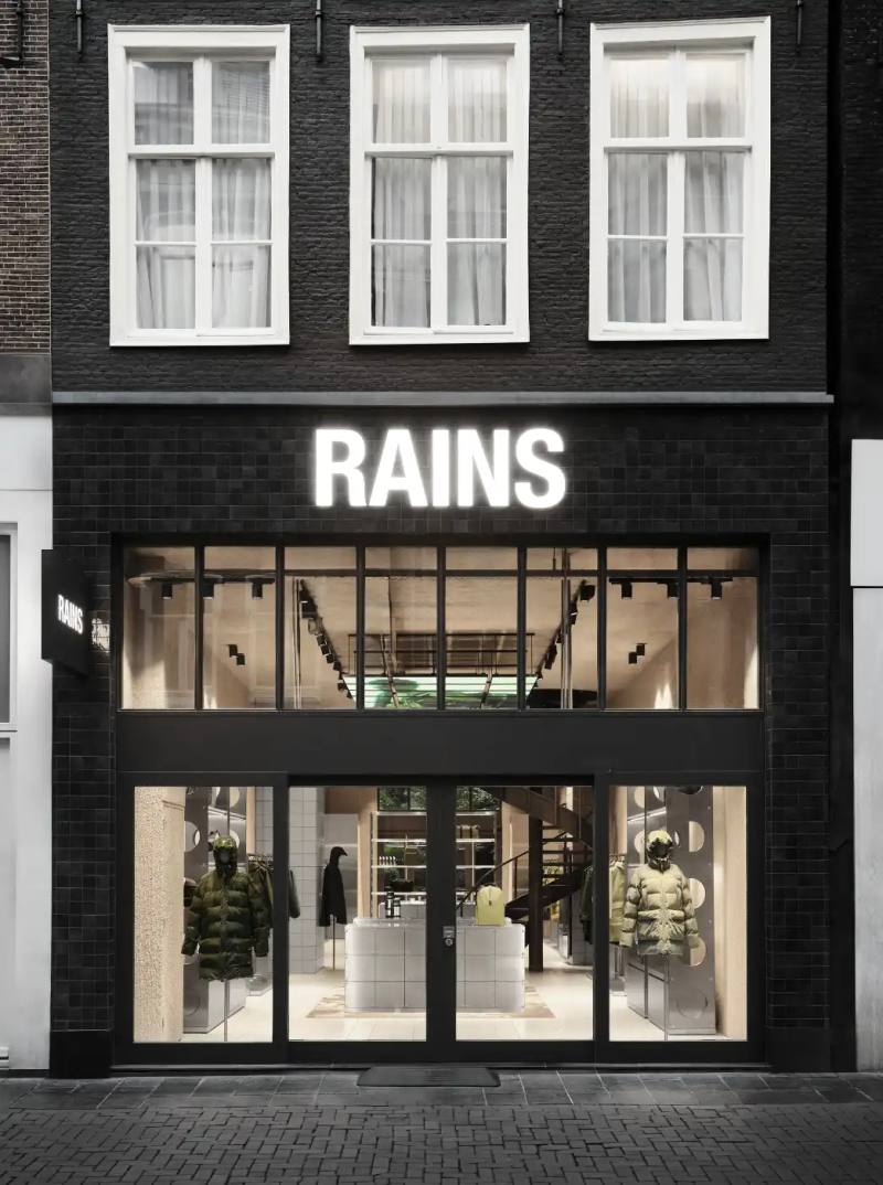 Rains contemporary lifestyle brand opens Amsterdam flagship store designed by Stamuli studio, featuring tiled grid system, custom furniture, and LED installations mimicking natural light.