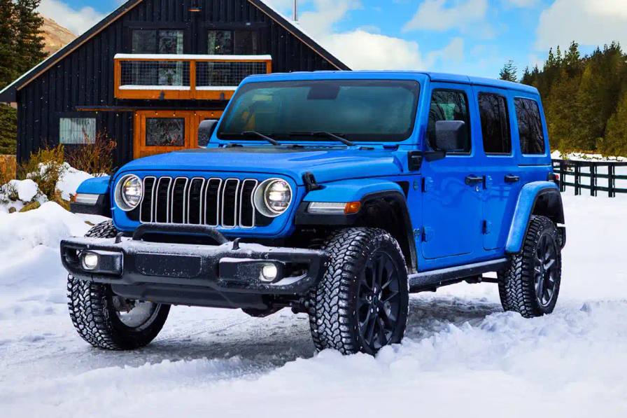  2025 Jeep Wrangler 4xe Backcountry in profile view, showing black exterior decals, 20-inch wheels with all-terrain tires, steel bumpers, and rock rails against a natural outdoor background.