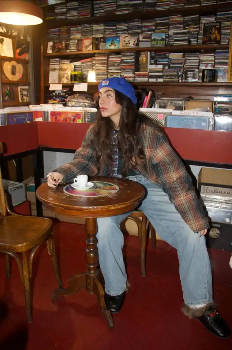 image of Ellynora, an Italian-American electronic artist who combines singing and DJing. The piece covers her multicultural background, creative process, performance style, and upcoming projects including her 99xcent brand that merges music with fitness events.