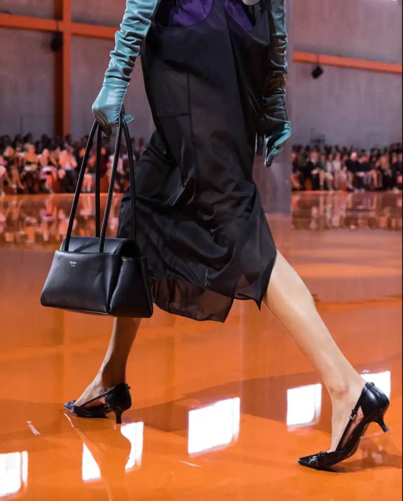 image about Prada's new Passage bag from the Spring/Summer 2026 collection, featuring a trapezoid shape, three pockets, and black leather construction.