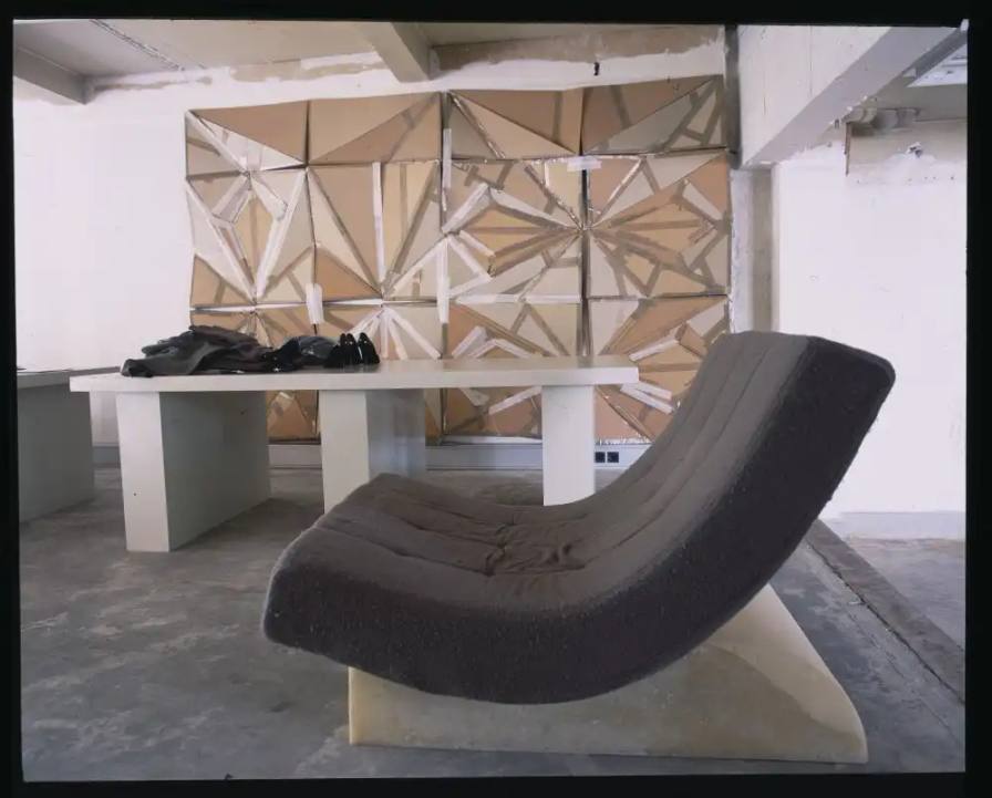 Interior of Rick Owens' brutalist Parisian home featuring unpolished floors, exposed wiring, a platform bed with Swiss Army blankets, and minimalist furnishings.