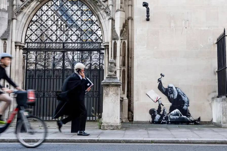 BANKSY TARGETS LONDON COURT BUILDING Banksy mural on court building exterior showing judge with gavel striking down protestor