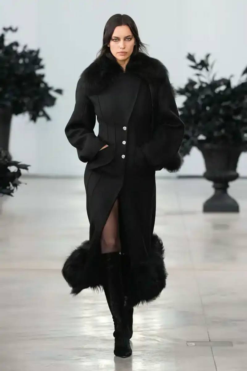 Models walking the runway at David Koma's debut Blumarine autumn/winter 2025 collection, showcasing sculptural neoprene pieces and bustier dresses in a palette of red, black, gray, and white against a minimalist backdrop at Milan Fashion Week.