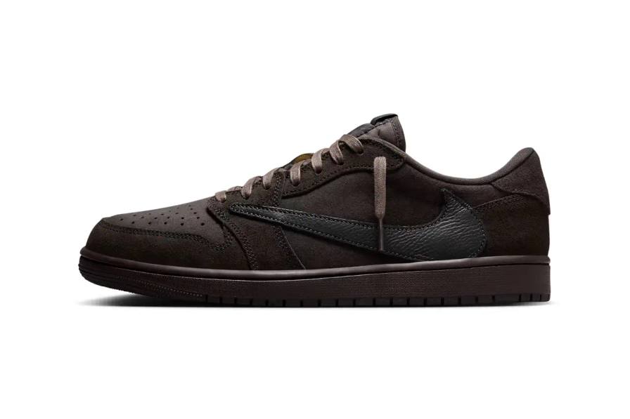 A detailed product shot of the Travis Scott x Air Jordan 1 Low OG "Dark Mocha" sneaker. The shoe features a dark mocha brown leather upper with black overlays, a distinctive reversed lateral Swoosh in tumbled leather, and Cactus Jack branding on the medial side. The sneaker sits against a neutral background, showcasing its intricate design details and color blocking.
