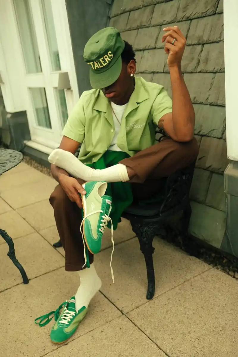 image of the new collaboration between Tyler, The Creator's GOLF le FLEUR* brand and Converse. The collection, named "1908" after Converse's founding year, features two archive shoe models: the Naut-1 from 1971 and the Coach Jogger from 1976, which was originally an Olympic running shoe. Tyler has redesigned both models with preppy elements, co-branded logos, pastel colors, and in some cases, the signature "Darryl" pattern featuring repeating Airedale Terrier images. This collaboration represents a new direction for their partnership by focusing on previously unused historical designs from Converse's archives. The collection will be available online starting June 20.