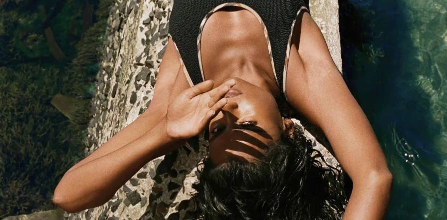 BURBERRY AND HUNZA G RELEASE ONE SIZE SWIMWEAR This image details a clothing collaboration between Burberry and Hunza G focusing on single size swimwear.