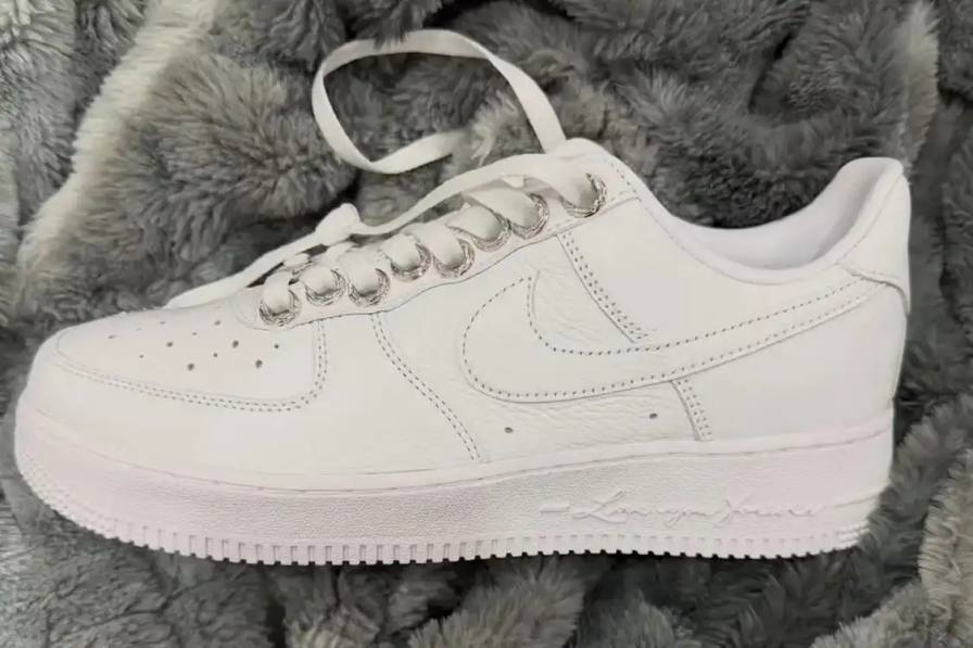 Triple collaboration sneaker featuring white leather construction with sterling silver hardware and engraved metal components.