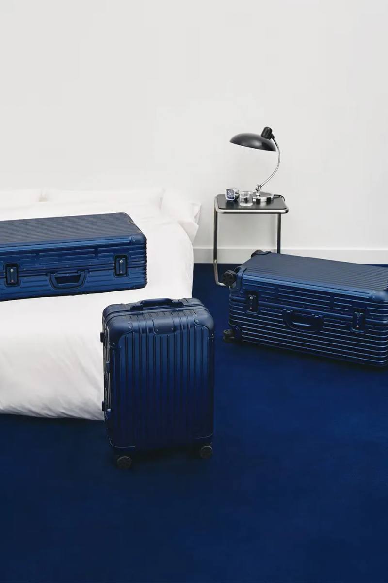 image announces the release of RIMOWA's permanent Ink Blue colorway for Original aluminium suitcases, detailing dimensions, pricing, and matching accessories.