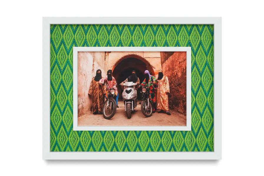 Portrait gallery wall showing Hassan Hajjaj's photographs in colorful recycled Moroccan floor mat frames. Models wear mixed pattern clothing against vibrant backgrounds.