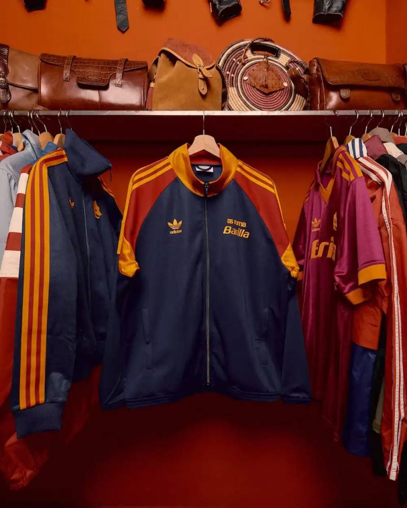 Image shows AS Roma 1990s retro football jersey in classic yellow and red colors, featuring Trefoil logo, Lupetto wolf emblem, and Barilla sponsor, representing Adidas Originals' heritage collection.