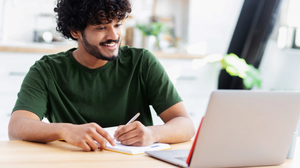 Man writing notes while applying for California LifeLine broadband pilot program online