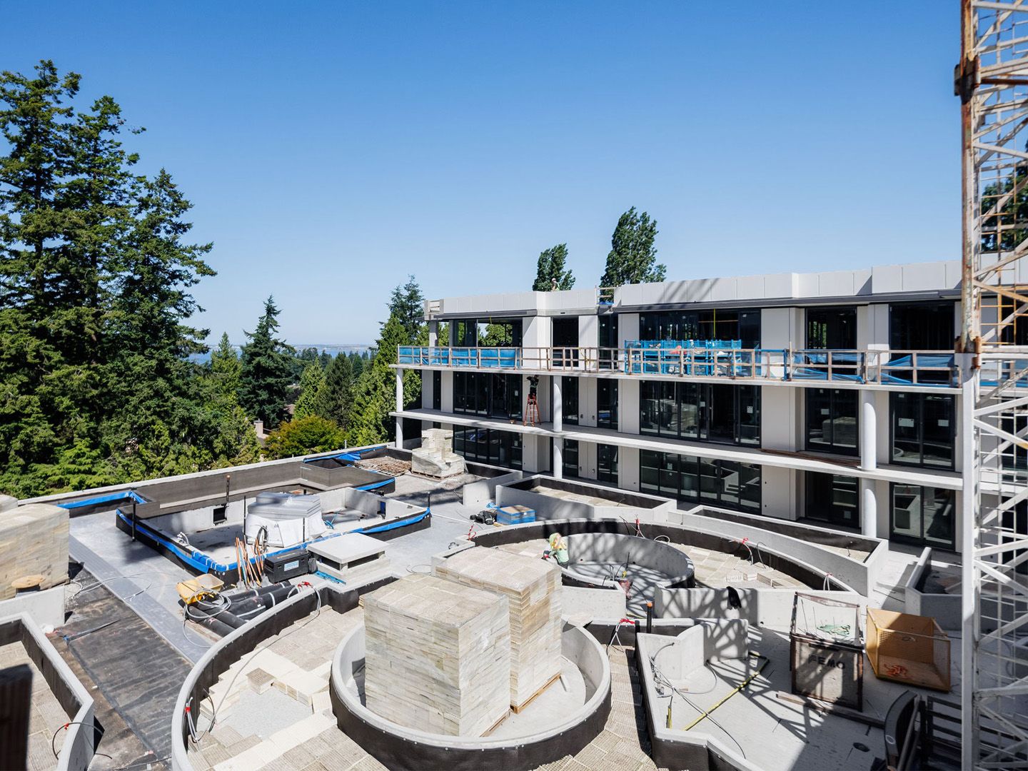Concrete residential building under construction in peaceful neighbourhood with trees and ocean views