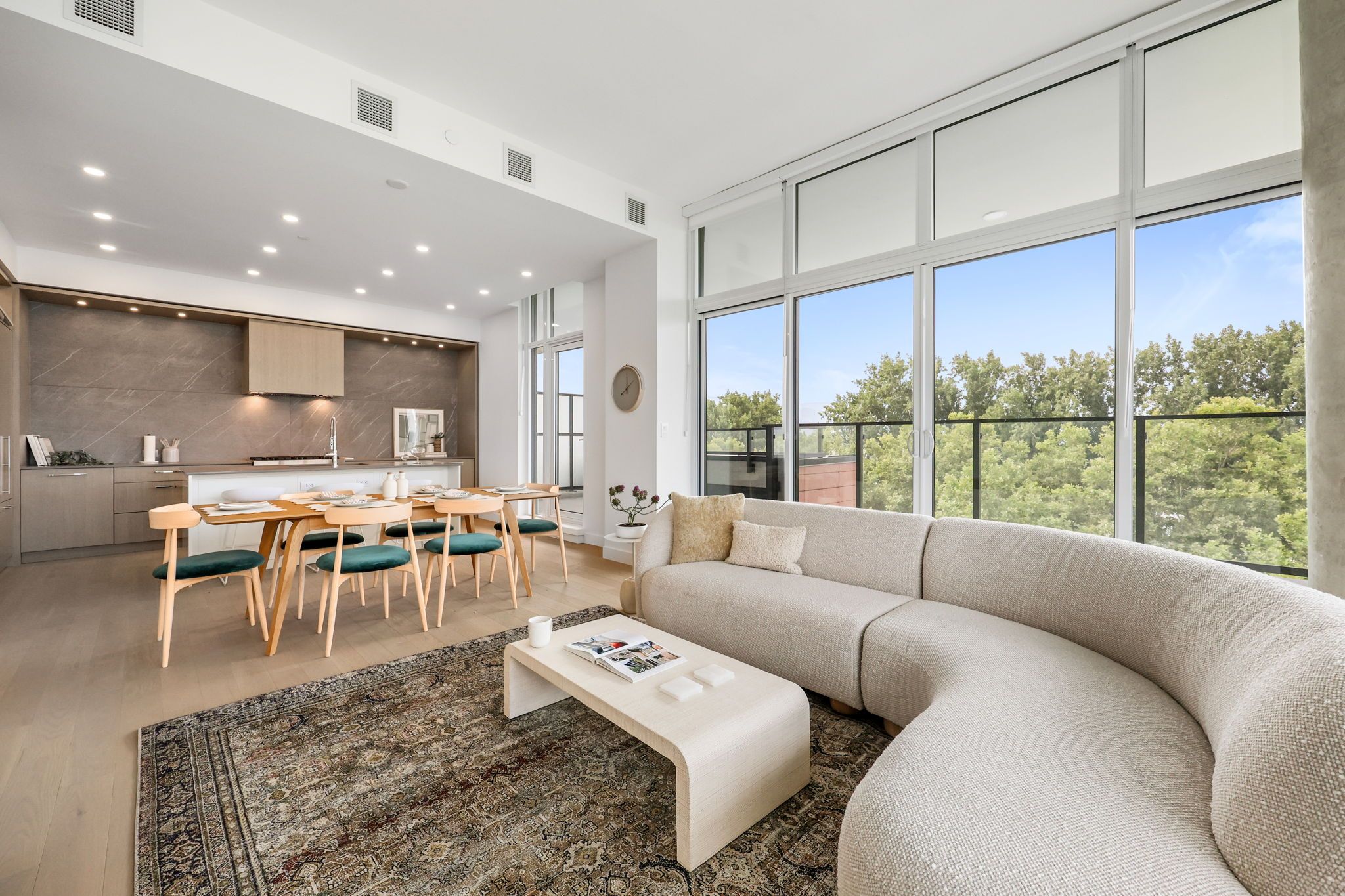 Perspective from living room looking towards kitchen with large windows and trees