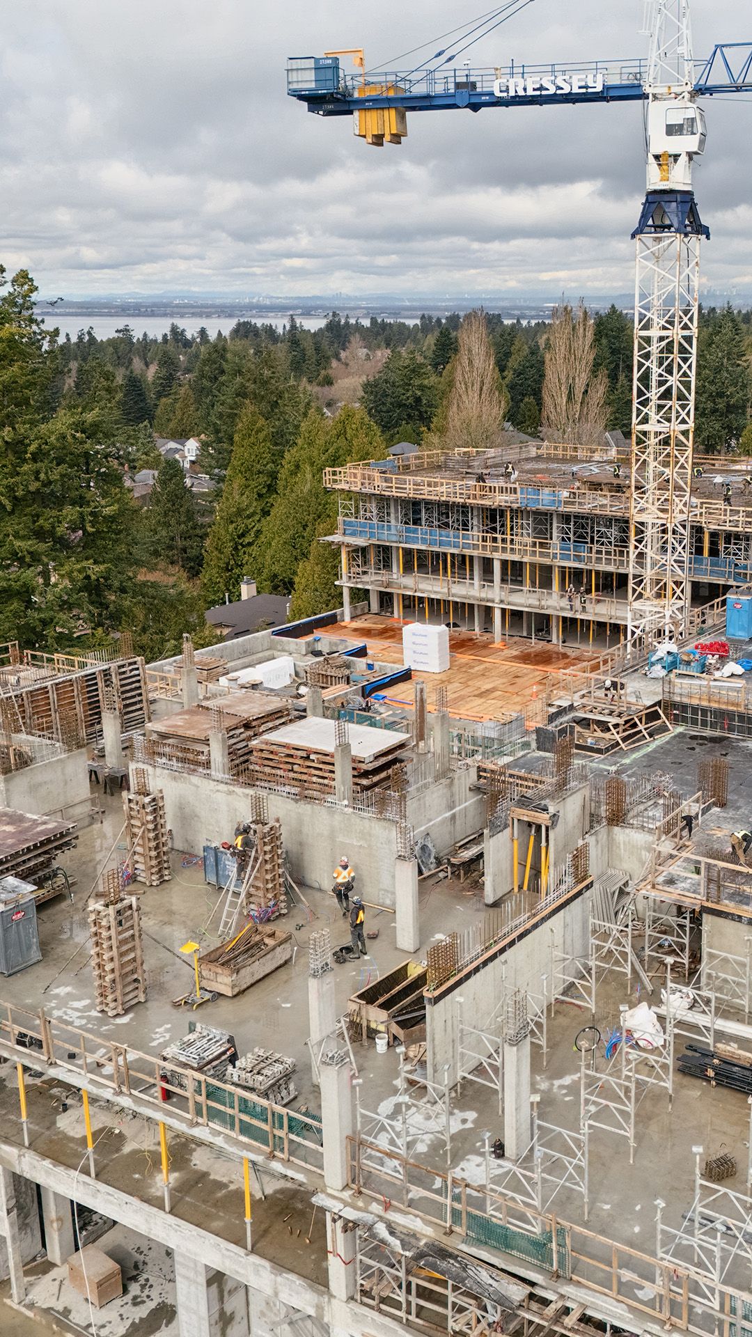 Close-up of concrete party wall installation on level 3 with crane in background