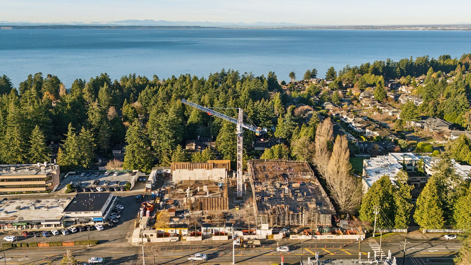 Residential building construction at sunrise surrounded by green trees and blue water