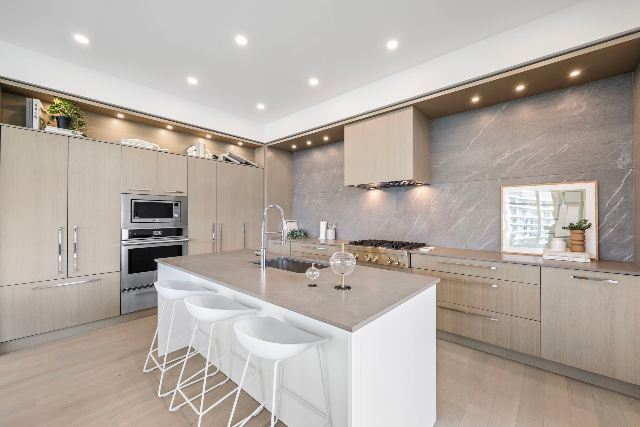 Large bright kitchen with stone backsplash, island, and appliance wall