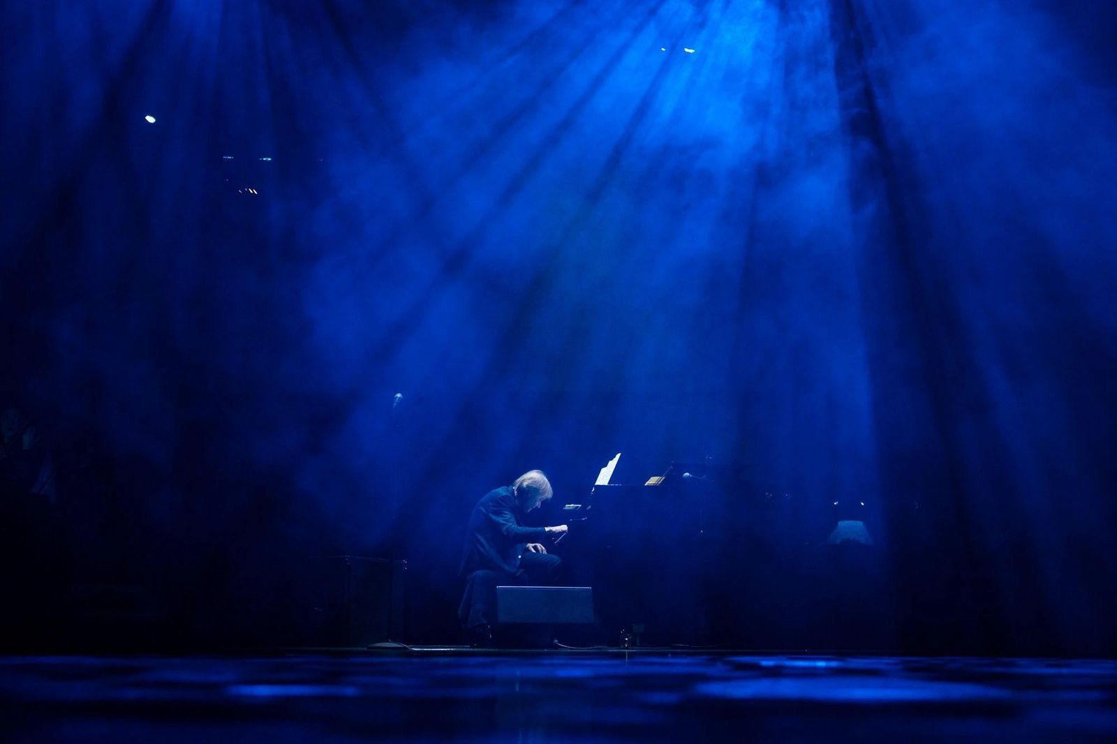 Richard Clayderman la București, Sala Palatului,  silueta la pianul de concert, scăldat în raze de lumină albastră, scenă plină de fum