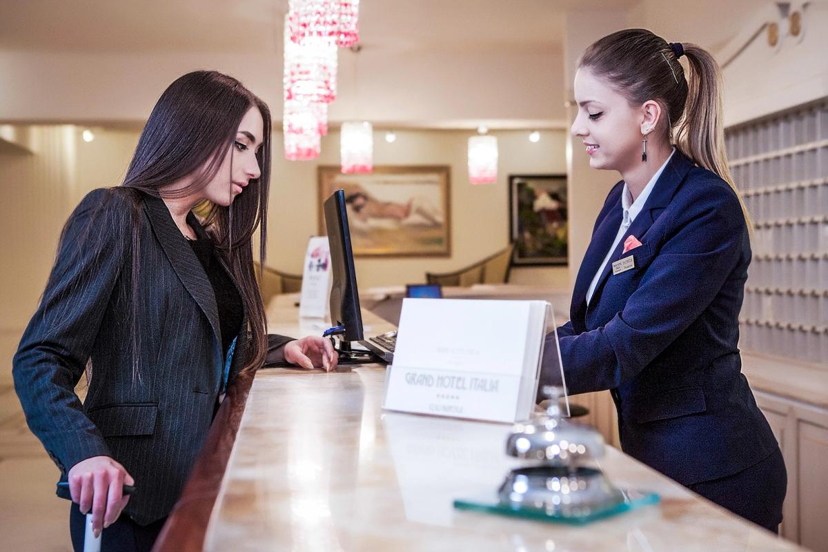 Recepția Grand Hotel Italia, Cluj — un moment de check-in. Marmură, candelabru de cristal, atmosferă de hotel premium.