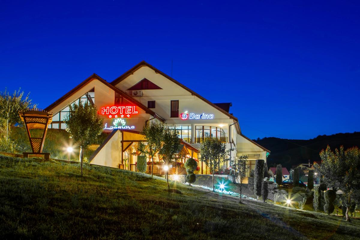 Hotel din lanțul Darina Hotels, Târgu Mureș — fațadă fotografiată la blue hour, semnalistică neon, peisaj transilvănean.
