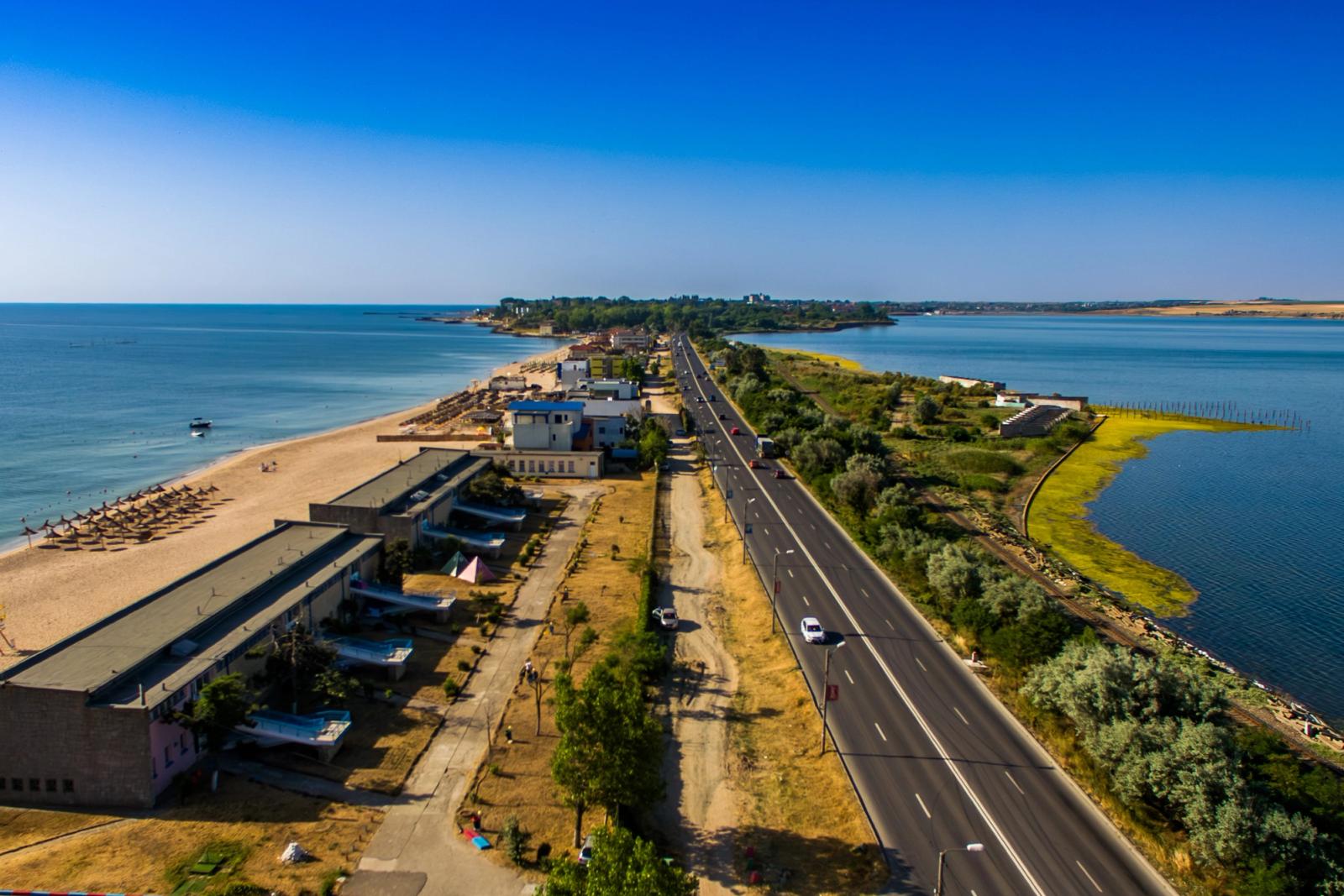 Vedere aeriană dinspre Eforie — plajă pe stânga, drumul DN39 pe mijloc, lagună pe dreapta. Hoteluri și pensiuni de-a lungul coastei.